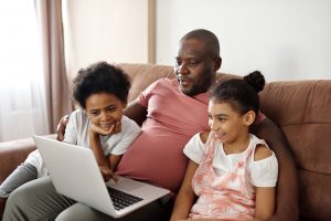 father and children looking at a laptop