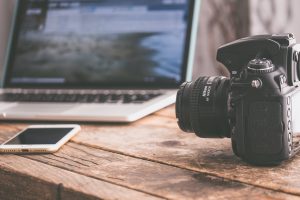 black dslr camera on beige wooden surface